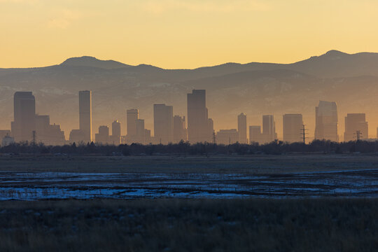 Photo of the downtown Denver city skyline at sunset, with the rocky mountains behind.