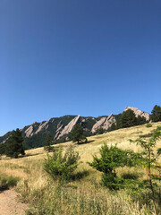 Flatiron mountains and gently sloping meadow with blue sky background and room for text at Chautauqua Park in Boulder, Colorado