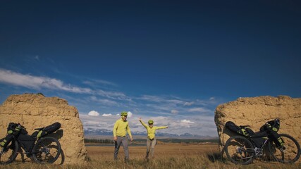 The man and woman travel on mixed terrain cycle bike touring with bikepacking. The two people...