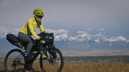 The woman travel on mixed terrain cycle touring with bikepacking. The traveler journey with bicycle...