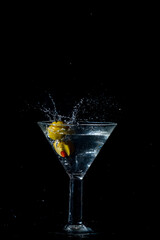Olive dropping and splashing into a martini glass