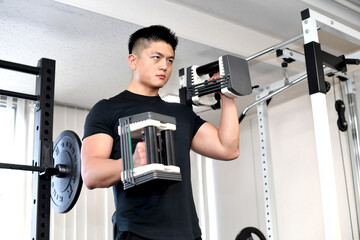 ジムでトレーニング（ダンベルカール）をする若い男性