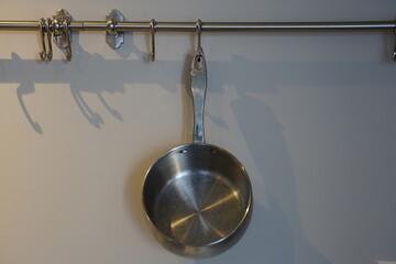 stainless steel pot hung on a rack against the wall