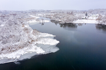 panoramic aerial view of the frozen snow-covered forest river. winter landscape with small village.