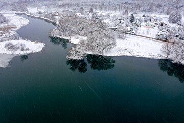 aerial view of village near frozen river. houses and trees covered by snow. winter rural landscape.
