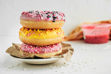 three tasty multi-colored pink and yellow very appetizing glazed donuts on kraft paper for delivery, vertical food content, selective focus
