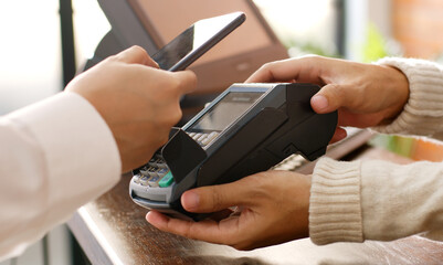 Customer using phone for payment at cafe restaurant, cashless technology and money transfer concept
