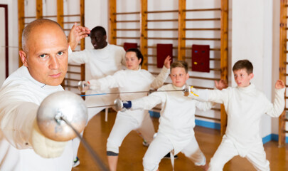 Man athlete training attack movements with rapier at fencing workout