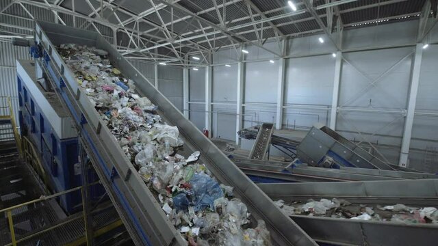 Waste sorting plant conveyors filled with various household waste.