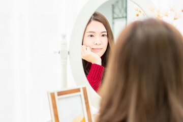 鏡の前で考え事をする若い女性