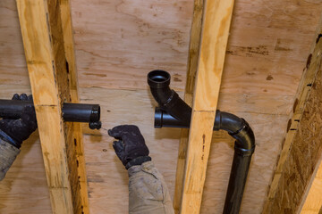 Worker using glue with fitting for installing the PVC drain pipe in the work area.