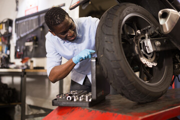 Afro american expert inspects the wheel of a motorcycle. High quality photo