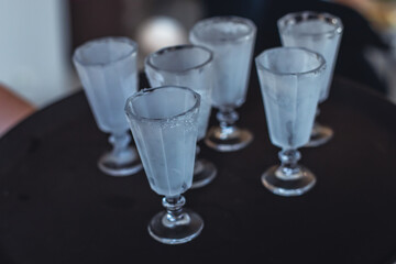 View of alcohol setting on catering banquet table, row line of ice cold vodka shots decorated catering bouquet table event