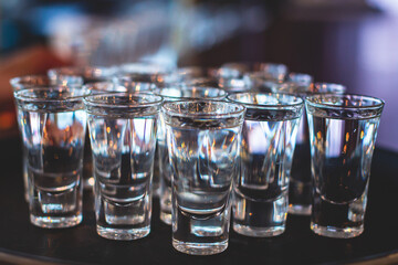 View of alcohol setting on catering banquet table, row line of ice cold vodka shots decorated...