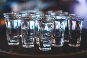 View of alcohol setting on catering banquet table, row line of ice cold vodka shots decorated catering bouquet table event