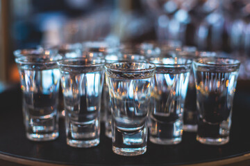 View of alcohol setting on catering banquet table, row line of ice cold vodka shots decorated catering bouquet table event