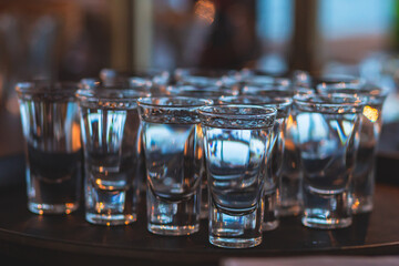 View of alcohol setting on catering banquet table, row line of ice cold vodka shots decorated catering bouquet table event