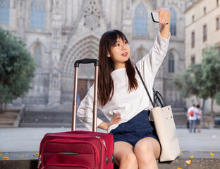Enthusiastic chinese female tourist making selfie on the background of landmark. High quality photo