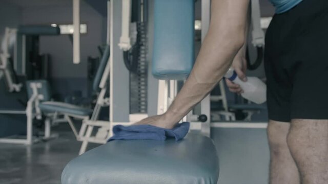 manos de un joven limpiando un aparato de gimnasio