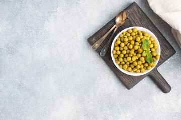 Canned peas in a plate on a wooden Board. Copy space.