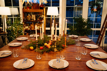 large square wooden table served for Christmas dinner. retro styled. Low light.