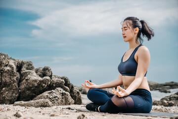 Fototapeta na wymiar Young Asian woman practicing yoga exercise at quiet rock pier with sea background. Sport and recreation in city rush.