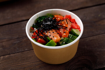 Hawaiian food dish, in a box on a wooden table. Pan-Asian cuisine to go or delivery in container. Close-up