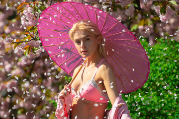 Beautiful girl in pink flowers in summer blossom park. Petals flowers.