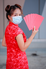Beautiful gorgeous Asian woman in traditional Chinese dress holding Ang Pow or red envelopes and...