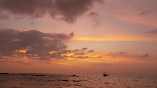 Patel sweet Pink colorful sky and a small silhouette fishing boat in sunset time. Cloudscape background timelapse footage. Orange clouds and golden sunlight sprayed over sky.nature landscapes 