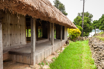 Fototapeta na wymiar Okinawa traditional house made of wood, grass thatched roof and coral wall.