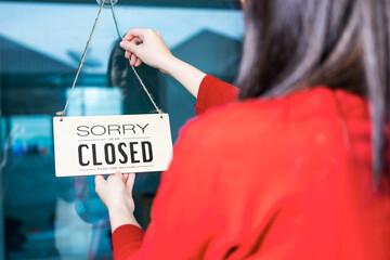 Asian woman shop owner hanging label 'Sorry we are Closed'. She close her shop under pandemic...
