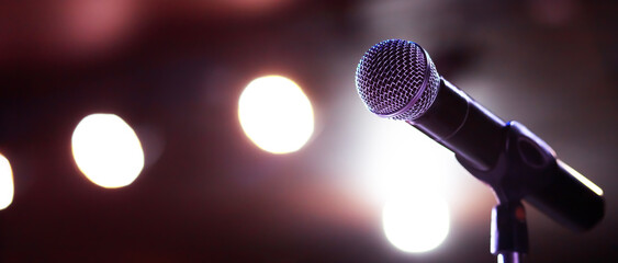 Close up of microphone on stage lighting at concert hall or conference room. copy space banner....