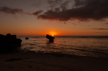 Vibrant orange colored sunsets with pink clouds descending the horizon behind a typical Okinawa...