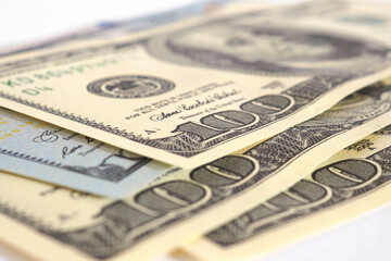 Several American hundred dollar bills lie on a white surface. Close-up. Old and new banknotes. Focus on the number 100. Economy, money, state allowance and savings in the USA. Macro