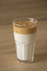 Glass with dalgona coffee on a wood table and wood background.