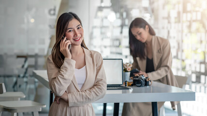 Asian business woman have the joy of talking on the phone, laptop and tablet on the office desk.