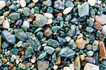 Colorful sea pebbles on the shore close up. Top view, flat lay. Abstract background texture, sea stones in water.