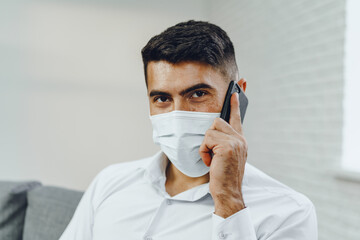 Handsome young businessman with face mask talking on the phone