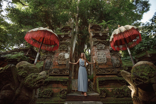 Young woman standing in temple gates at  temple in Bali, Indonesia. Beautiful nature place in Bali, travel concept