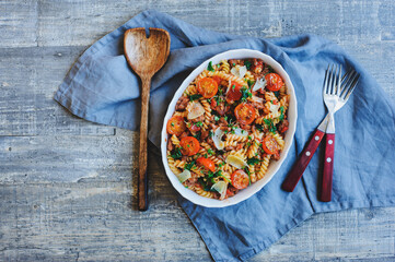 cooking tasty comfort food - italian fusilli pasta baked with meat sauce, cherry tomatoes and cheese