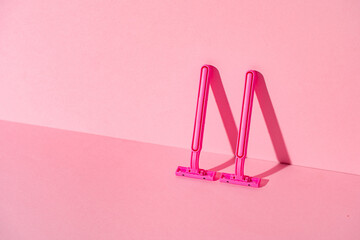 Pink disposable razors on pink background, copy space