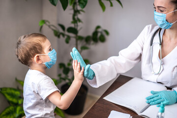 A little boy patient is visiting the pediatrician's office and high five the doctor. Concept of a friendly atmosphere at the doctor's examination