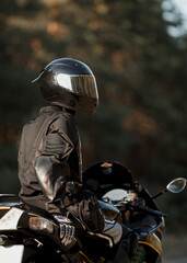 Fototapeta premium Biker in a helmet and leather protective equipment sits on a motorcycle, a sporty fast motorcycle