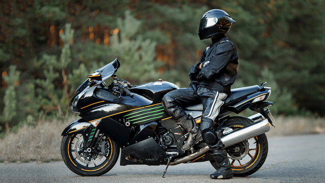 Biker in a helmet and leather protective equipment sits on a motorcycle, a sporty fast motorcycle