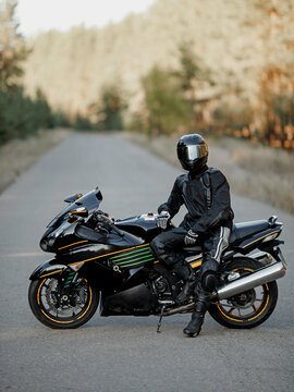 Biker in a helmet and leather protective equipment sits on a motorcycle, a sporty fast motorcycle
