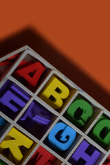 Colourfull Wooden Alphabets in A Wooden Box Organiser, isolated with Orange Background