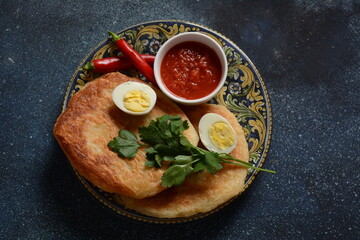 Traditional dishes of Israeli and Middle Eastern cuisine - Malawach with hard boiled eggs and tomatoes.  Malawach or malawah: traditional fried bread of Yemenite Jews