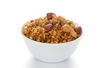 'Shahi Mixture' in a white ceramic bowl, made with peanut, cashew, corn flakes, almonds, etc. Pile of Indian spicy snacks (Namkeen). Side view, against the white background