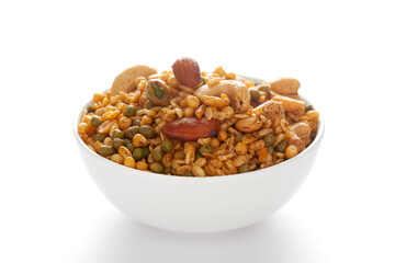 'Shahi Mixture' in a white ceramic bowl, made with peanut, cashew, corn flakes, almonds, etc. Pile of Indian spicy snacks (Namkeen). Side view, against the white background